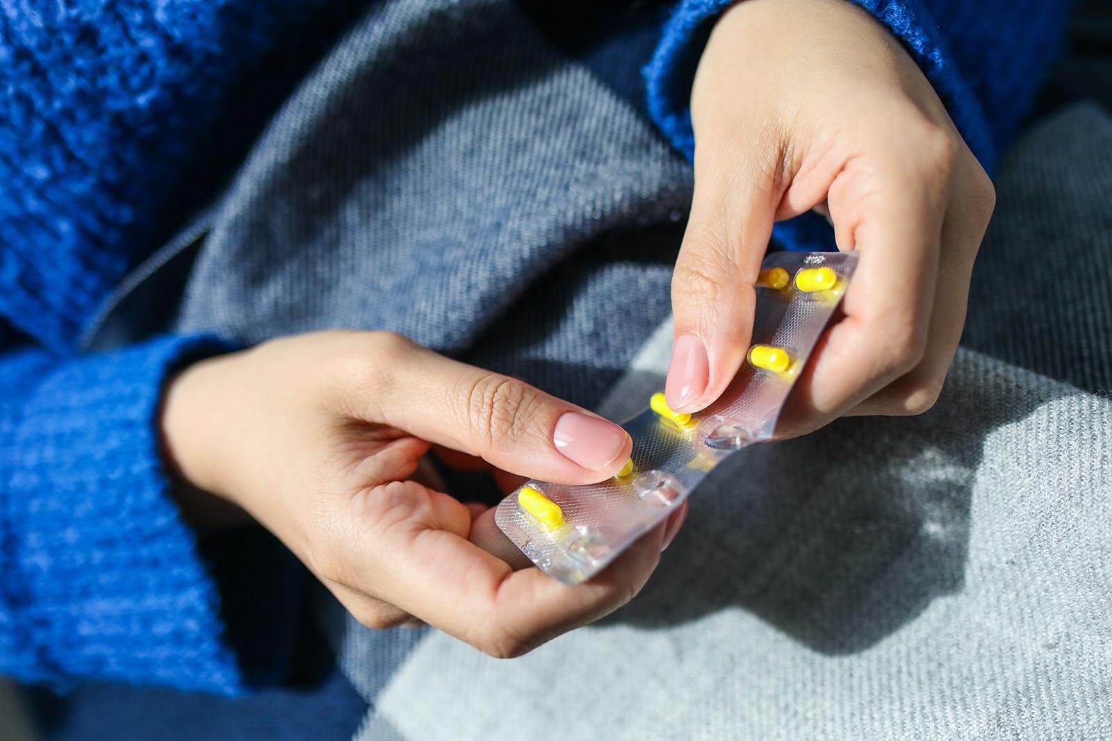 Frau nimmt Tabletten aus Blister, um Heuschnupfen zu bekämpfen