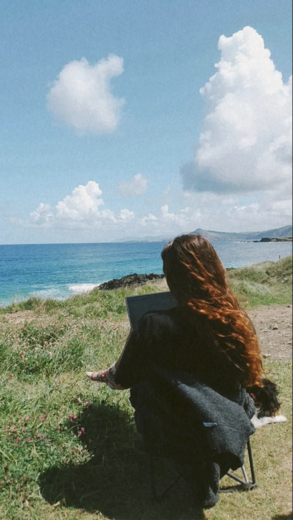 Mädchen sitzt auf Klippe am Meer und lebt Vanlife