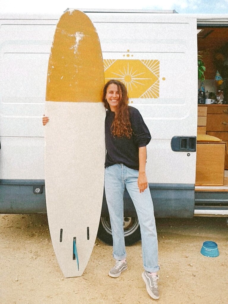 Mädchen mit Surfboard lebt Vanlife