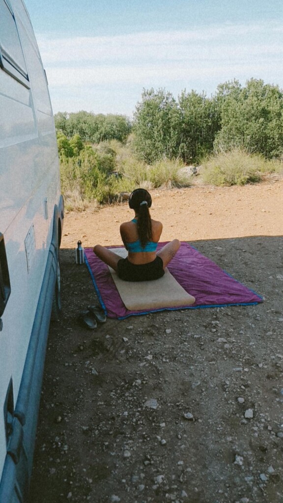 Mädchen macht Yoga neben Campervan