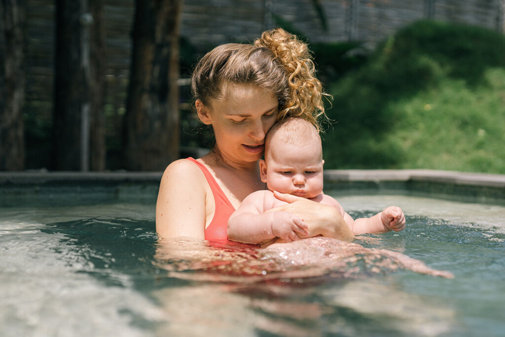 Junge Mama badet mit ihrem Baby im Pool