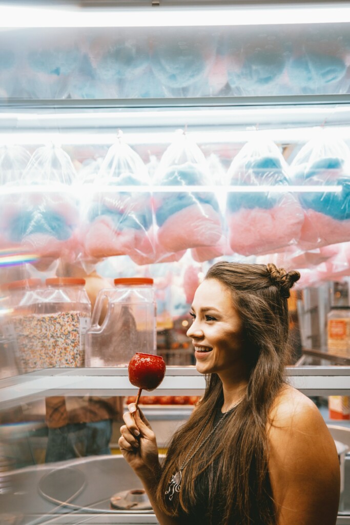 Junge Frau auf dem Jahrmarkt mit Zuckerapfel in der Hand